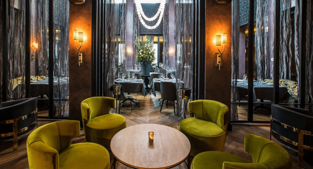 A fancy resturant with yellow green sofa and coffee table surrounded by dimmed lights.