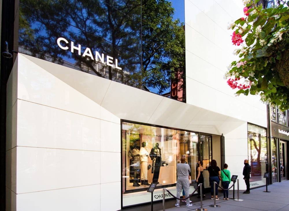 A group of people are standing outside of a Chanel store.