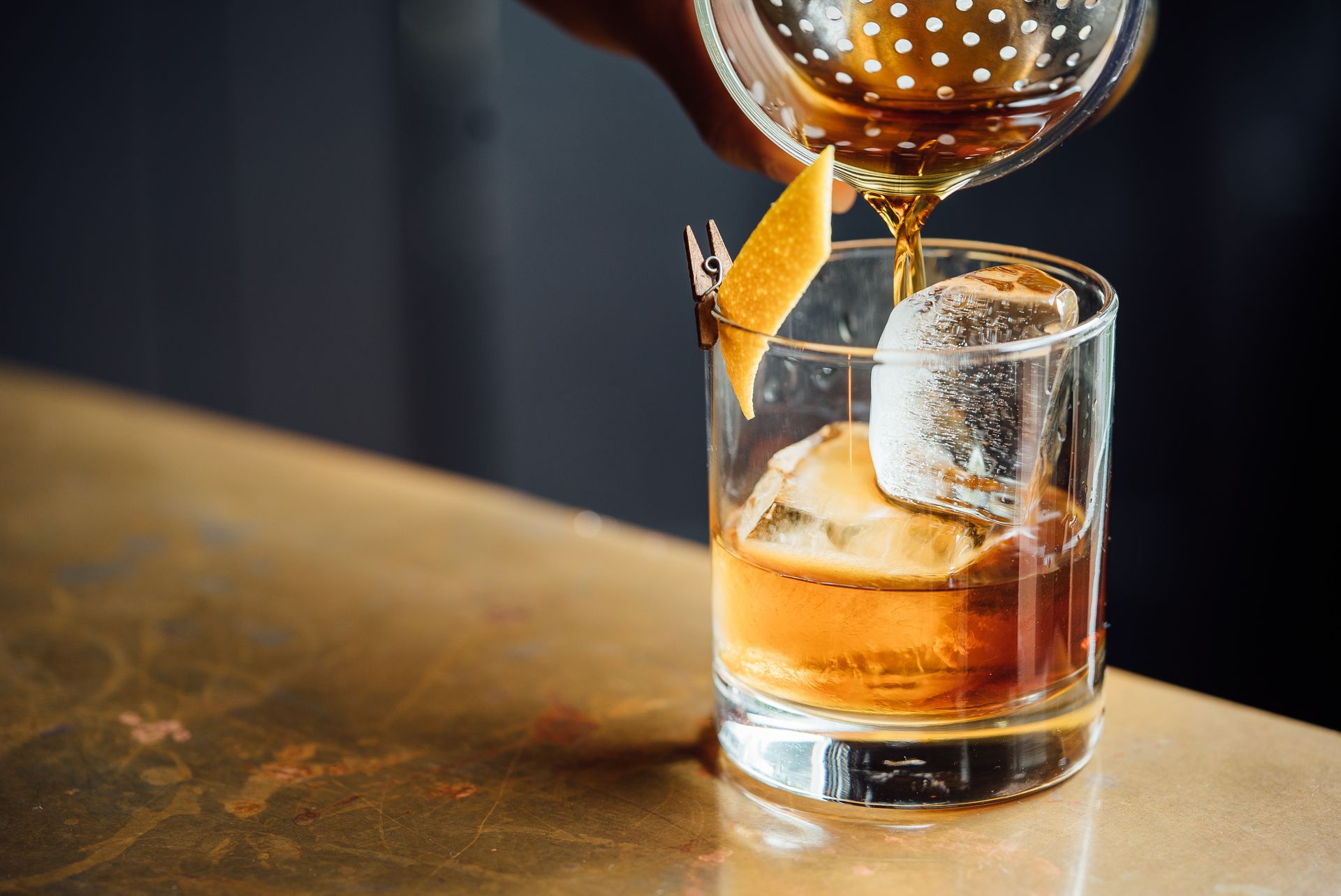 A person is pouring a drink into a glass with ice.