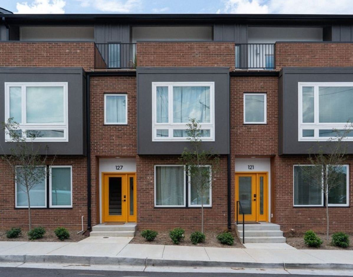 Row of brick townhouses with gray accents and yellow front doors.