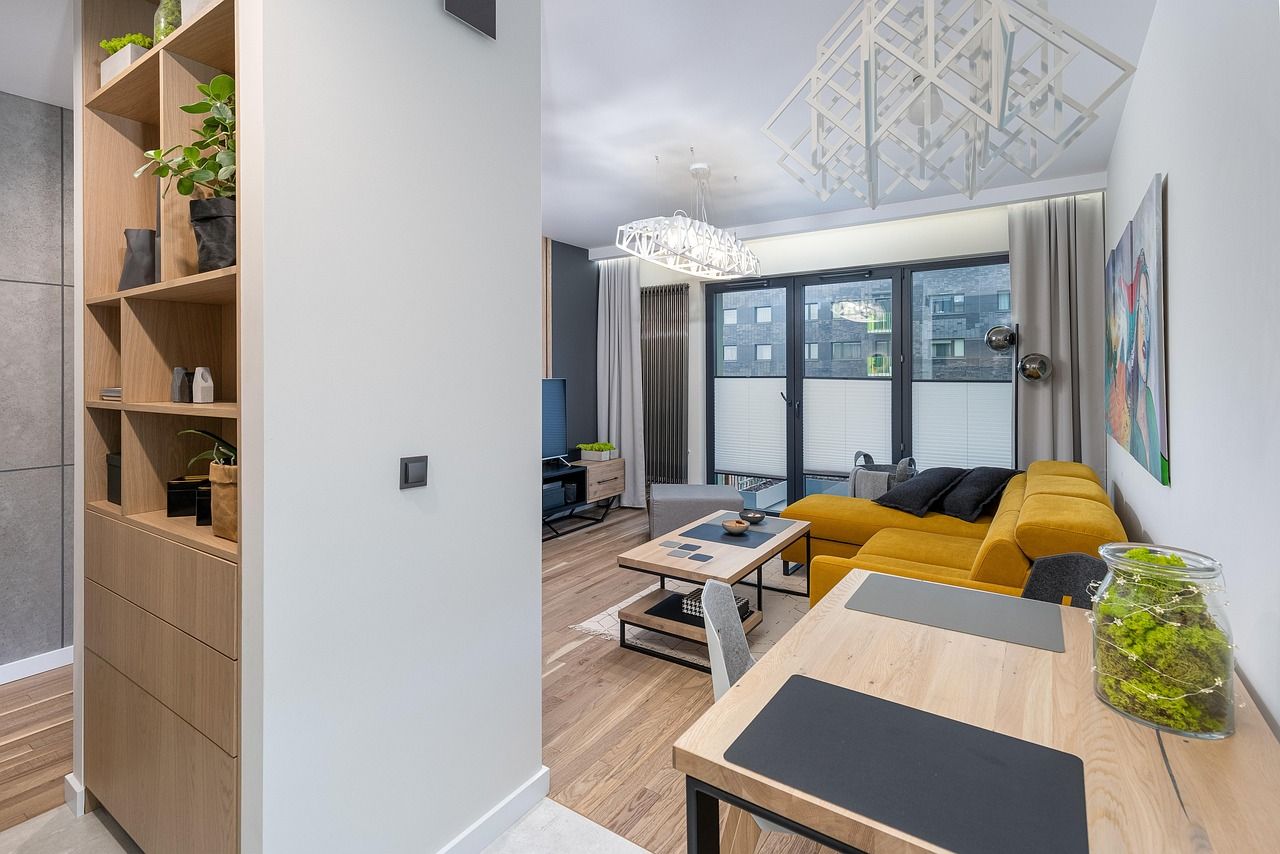 Living room with yellow sofa, wooden table, and built-in shelving unit.