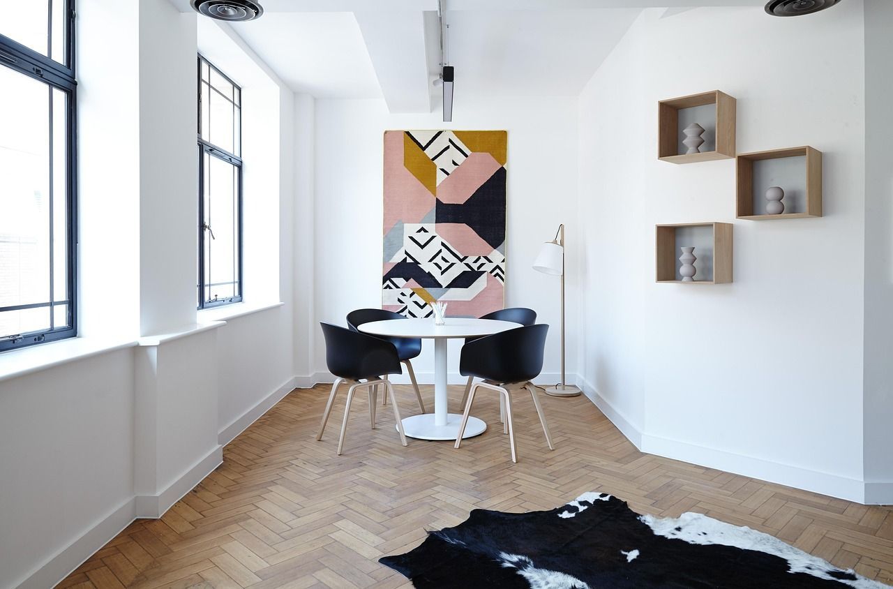 Dining area with a round white table, black chairs, art, wooden floors, and a cowhide rug.
