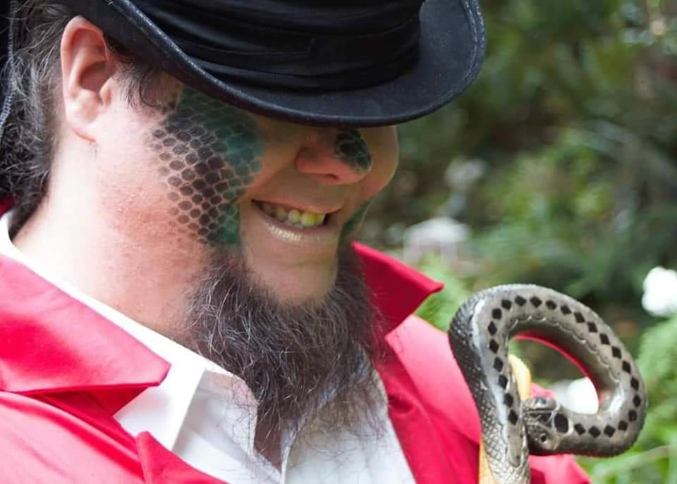 A man with a beard wearing a top hat and holding a snake staff, representing Fortuna.