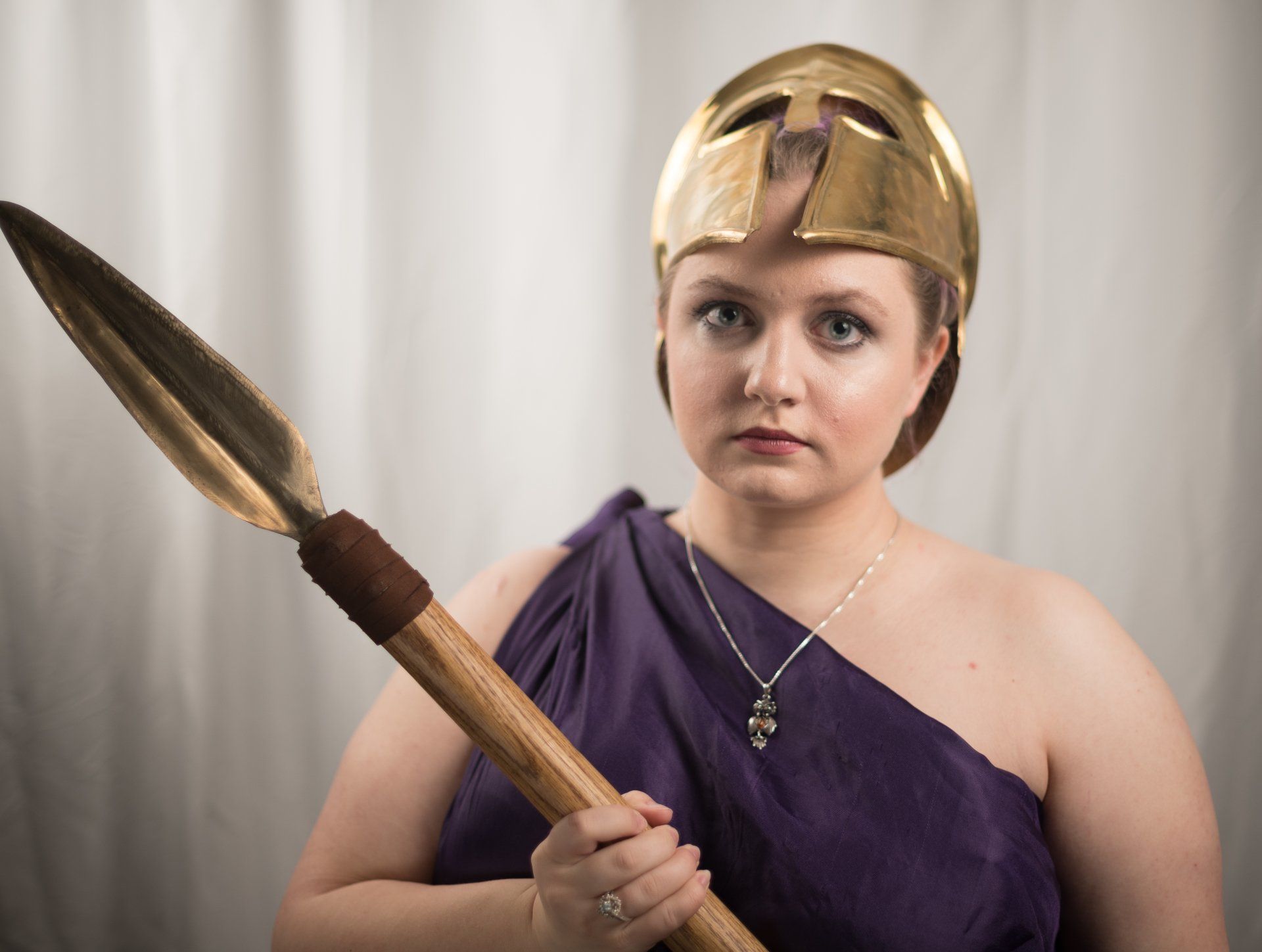 A woman in a purple toga, holding a spear, and wearing a helmet, representing Athena.