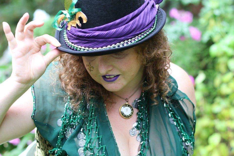 A woman wearing a purple top hat and a green dress, representing Fortuna.
