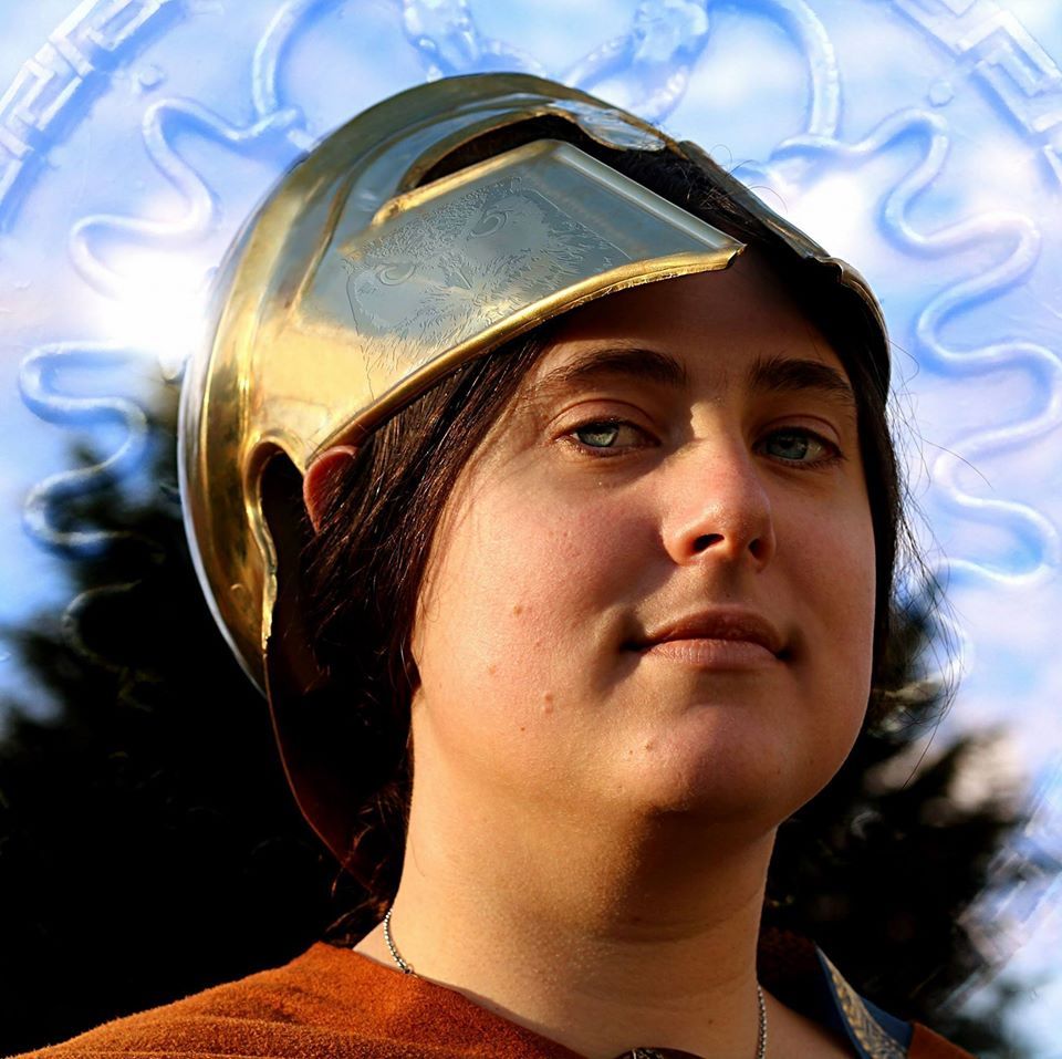 A woman wearing a helmet looks at the camera, representing Athena.