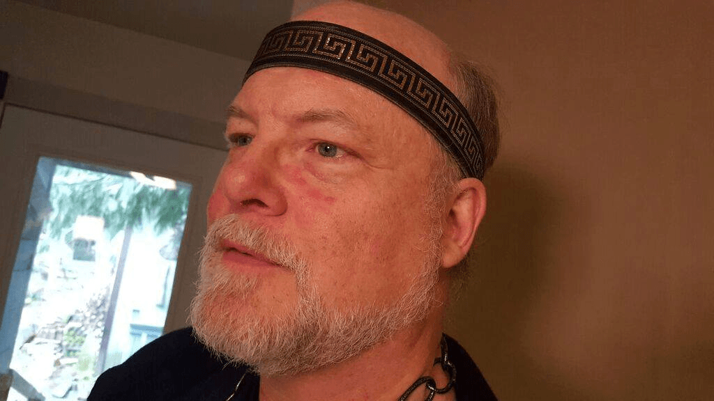 A man with a beard and a headband on his head,  representing Hades.