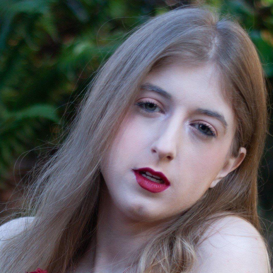 A close up of a woman 's face with long hair and red lipstick, representing Aphrodite.