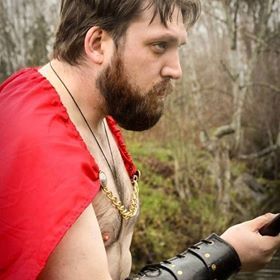 Man wearing a red cape and beard, representing Ares.