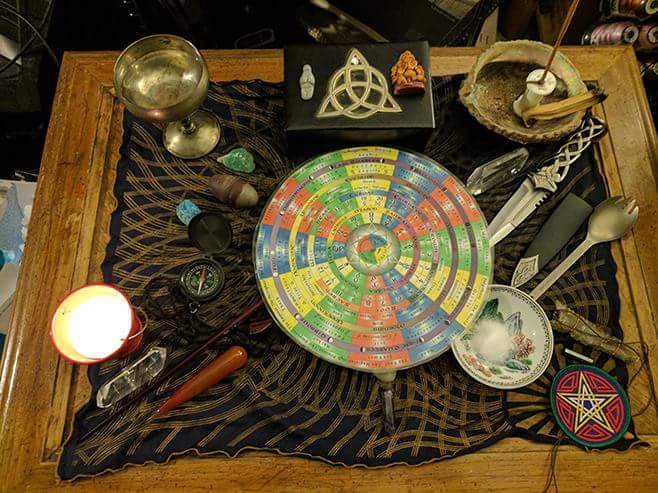 A wooden table topped with a circular wheel and various ritual objects.