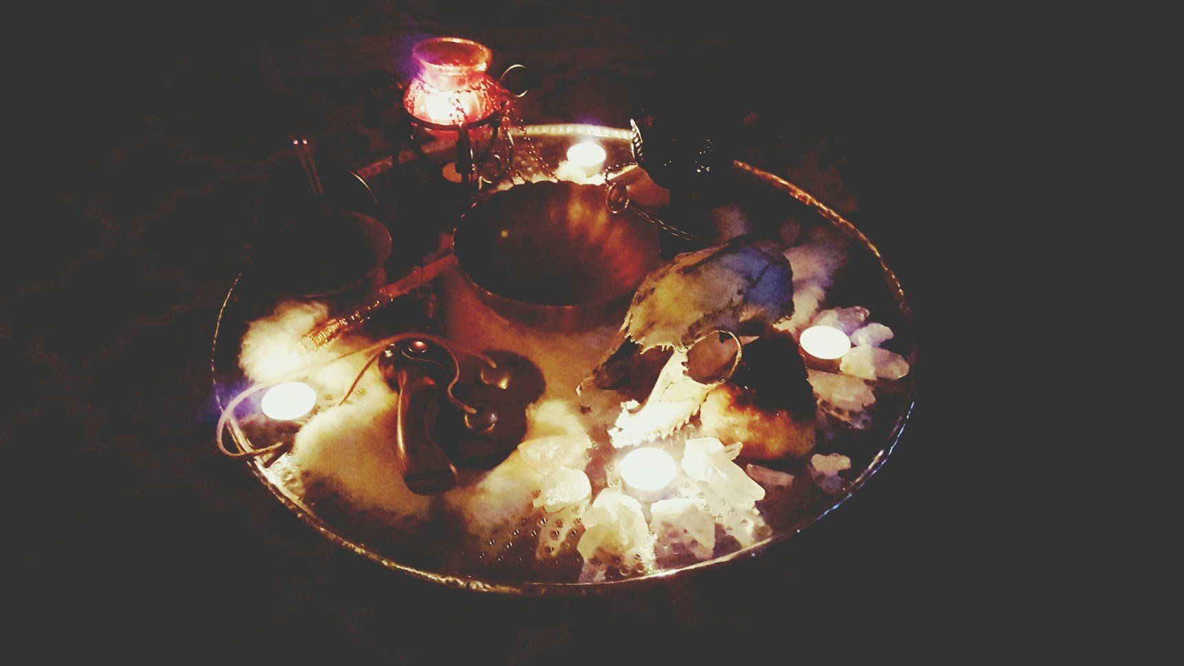 A bowl filled with candles and crystals in a dark room.