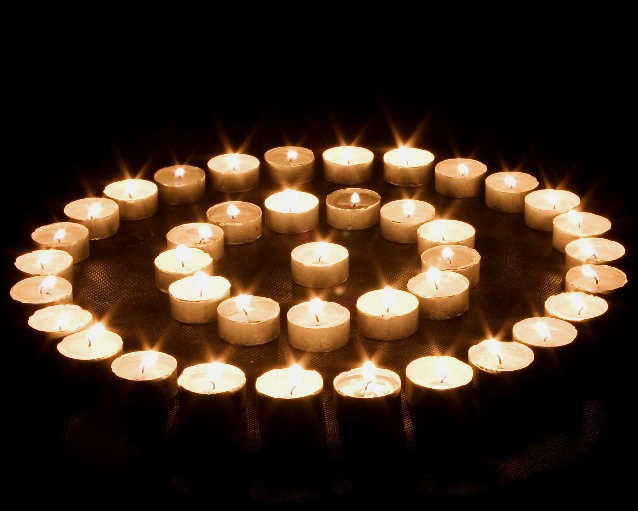 A circle of lit candles in the dark