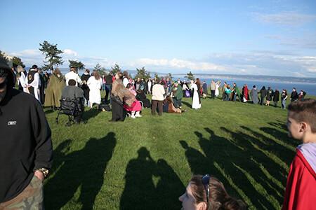 A group of people standing on top of a grassy hill for a gathering for the Aquarian Tabernacle Church.