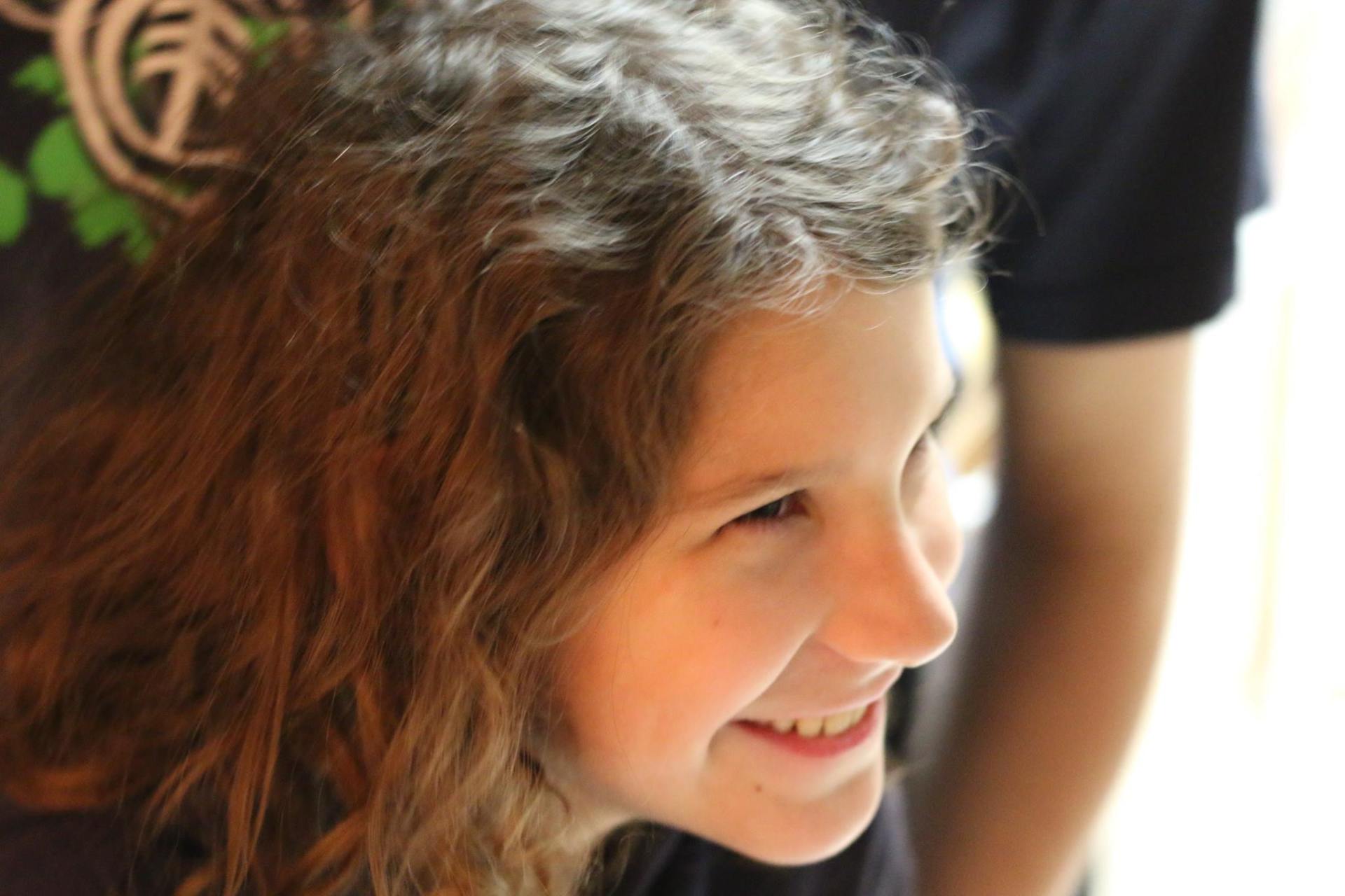 A young girl with curly hair is smiling for the camera.