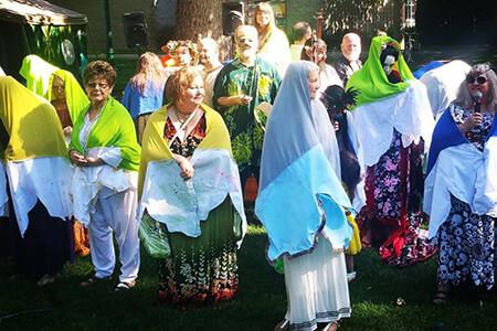 A group of people are standing in the grass covered in shawls.