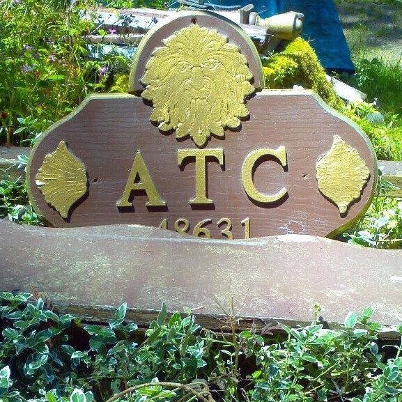 A wooden sign that says atc on it from the Aquarian Tabernacle Church.