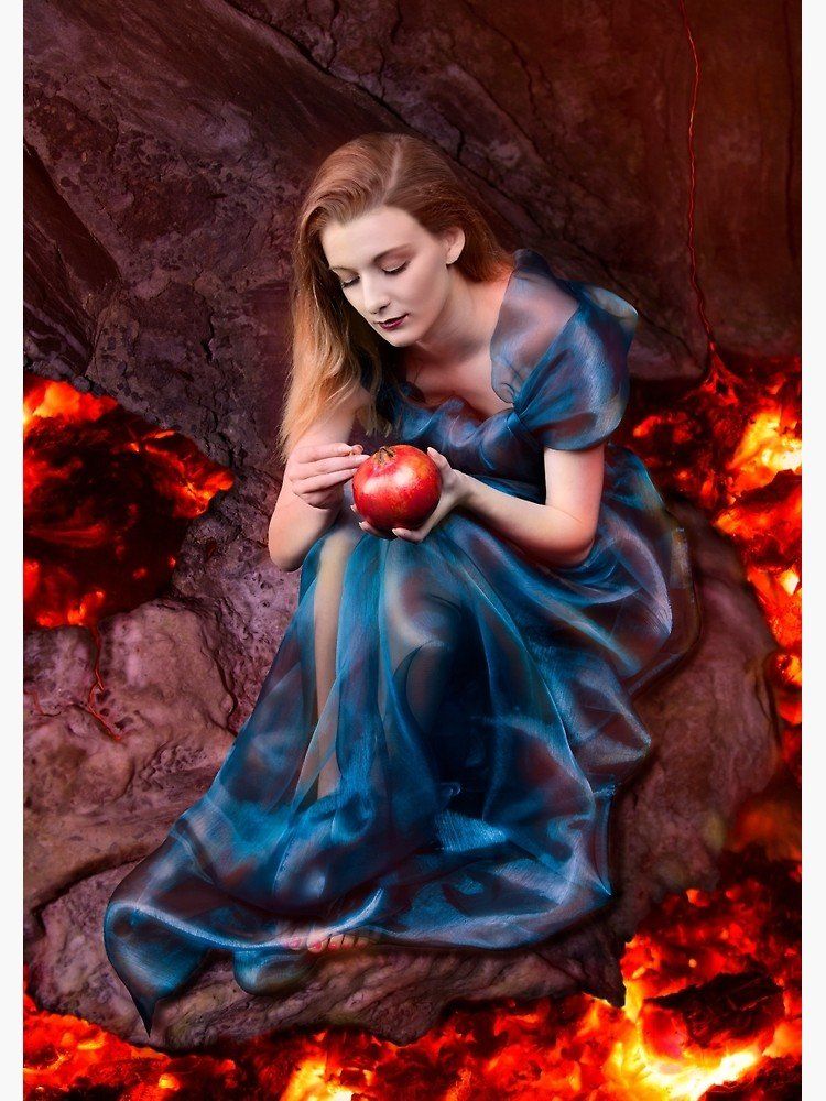 A woman in a blue dress is sitting on a rock holding a pomegranate representing Persephone.