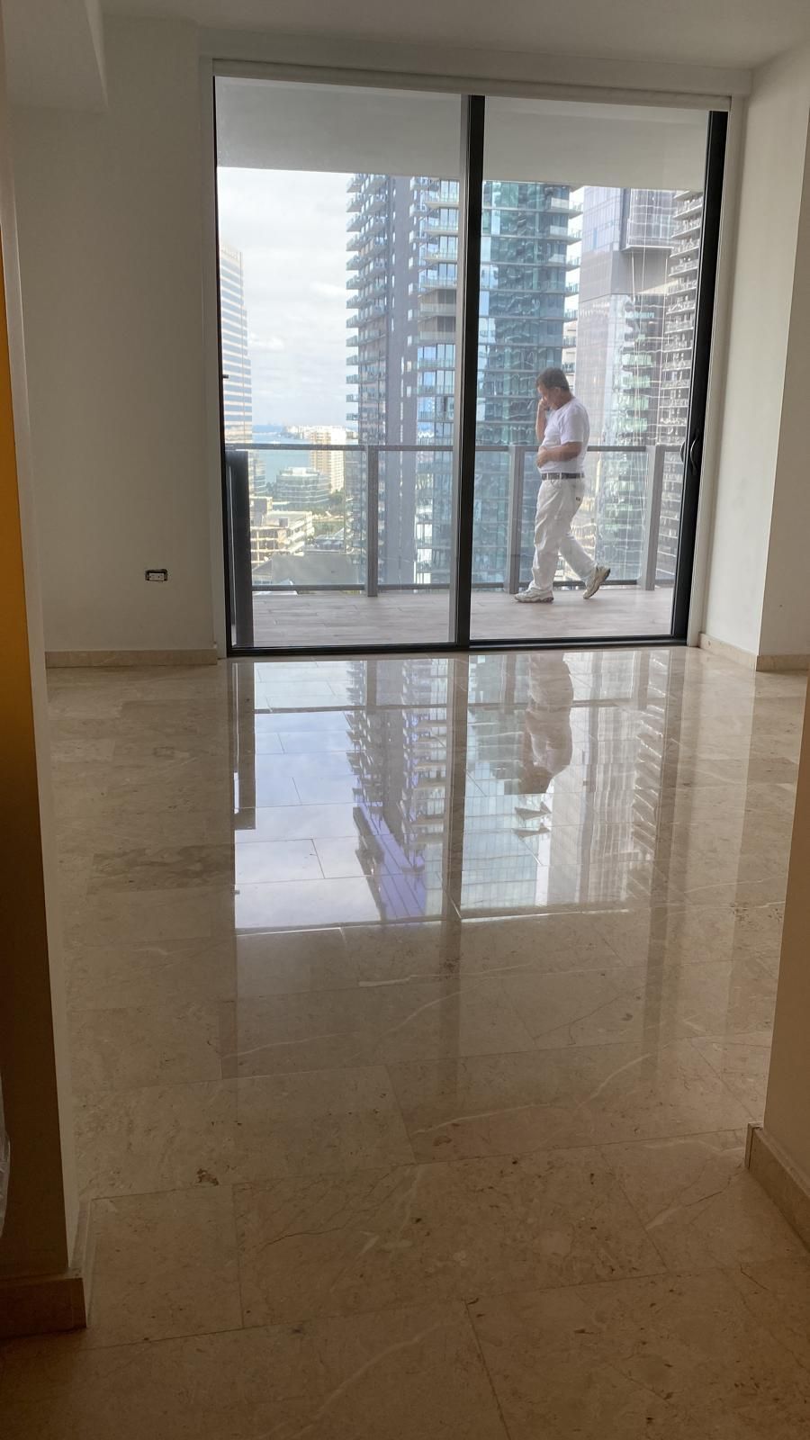 A man is standing on a balcony in an empty apartment.