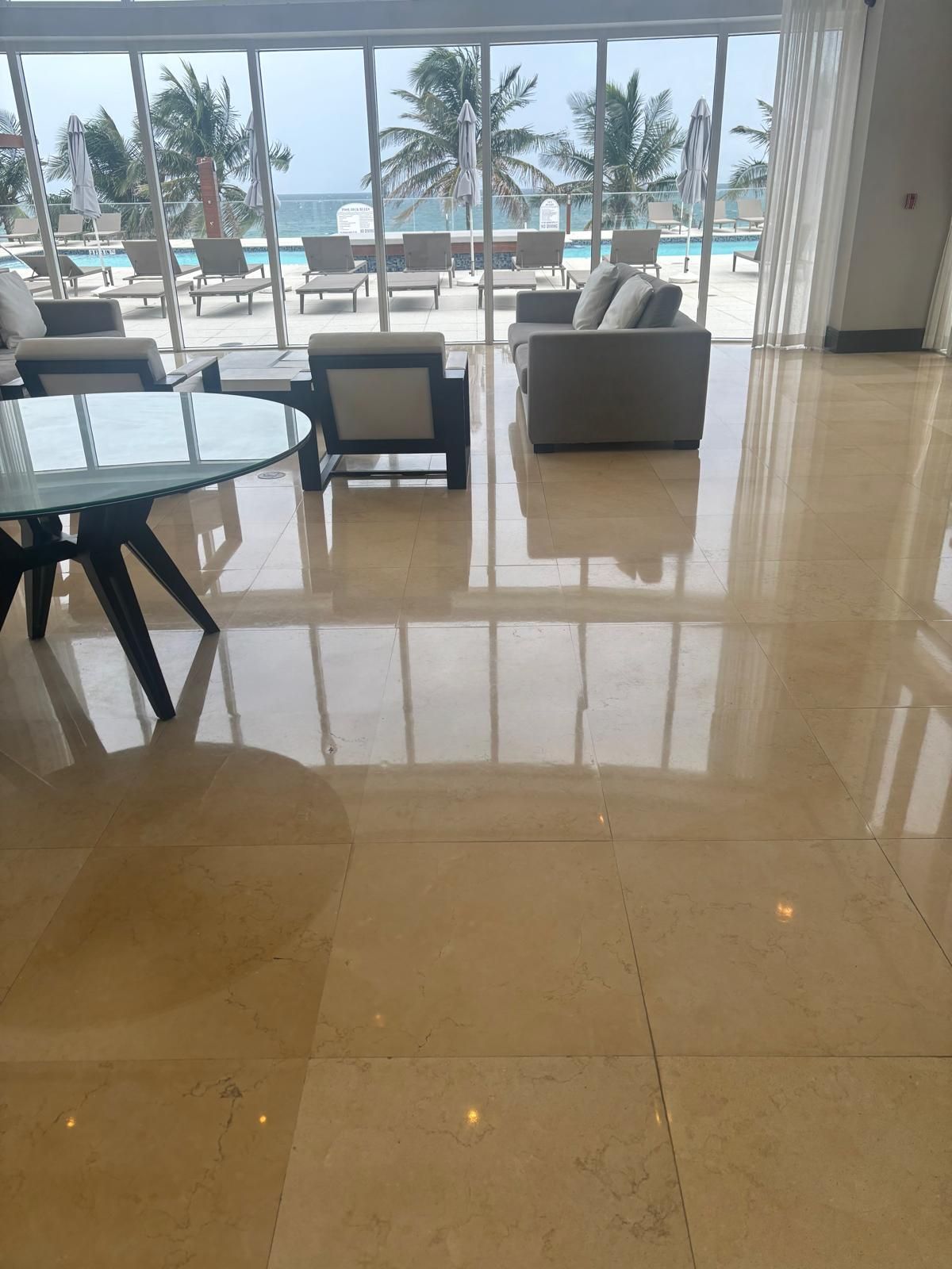 A living room with a table , chairs , and a large window overlooking the ocean.