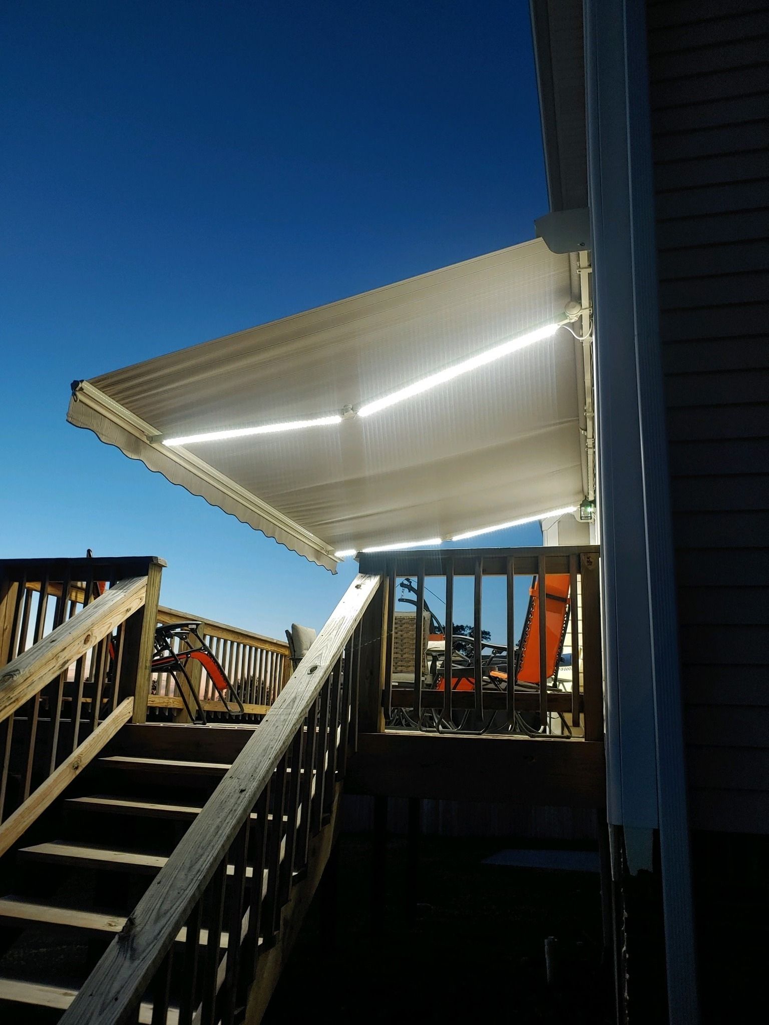 Wooden deck with stairs, awning overhead, sunny day.