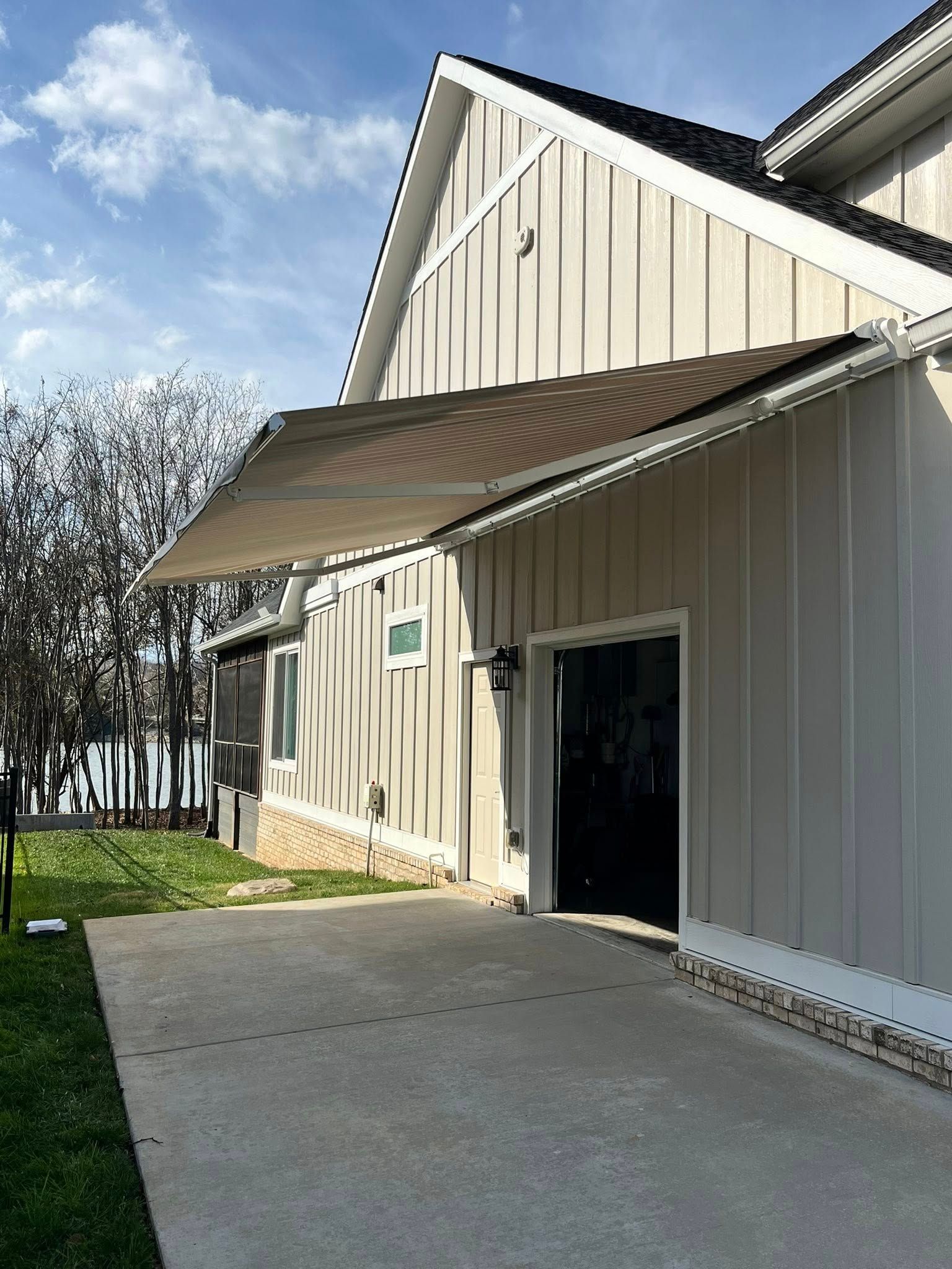 Exterior of a light beige building with an extended awning over a concrete driveway.
