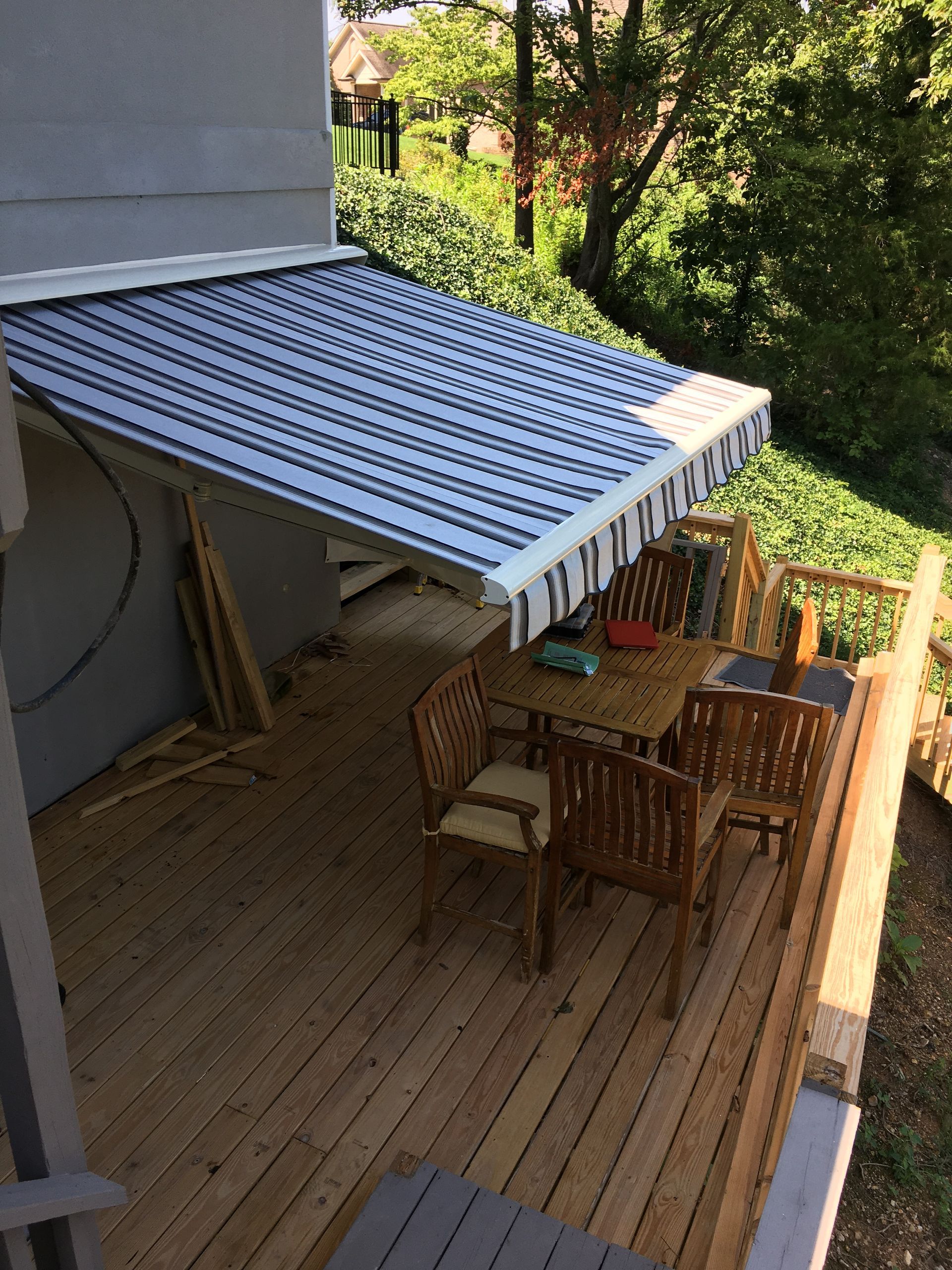 Wooden deck with outdoor furniture under a striped awning.