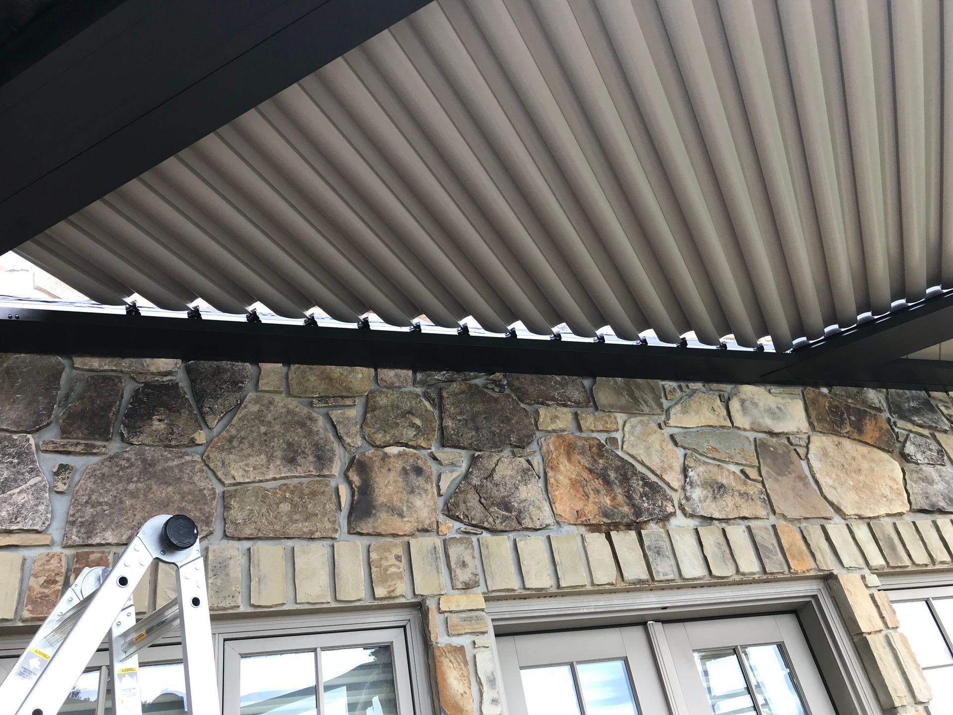Stone wall with beige corrugated ceiling and a black frame. A ladder is in the lower left.