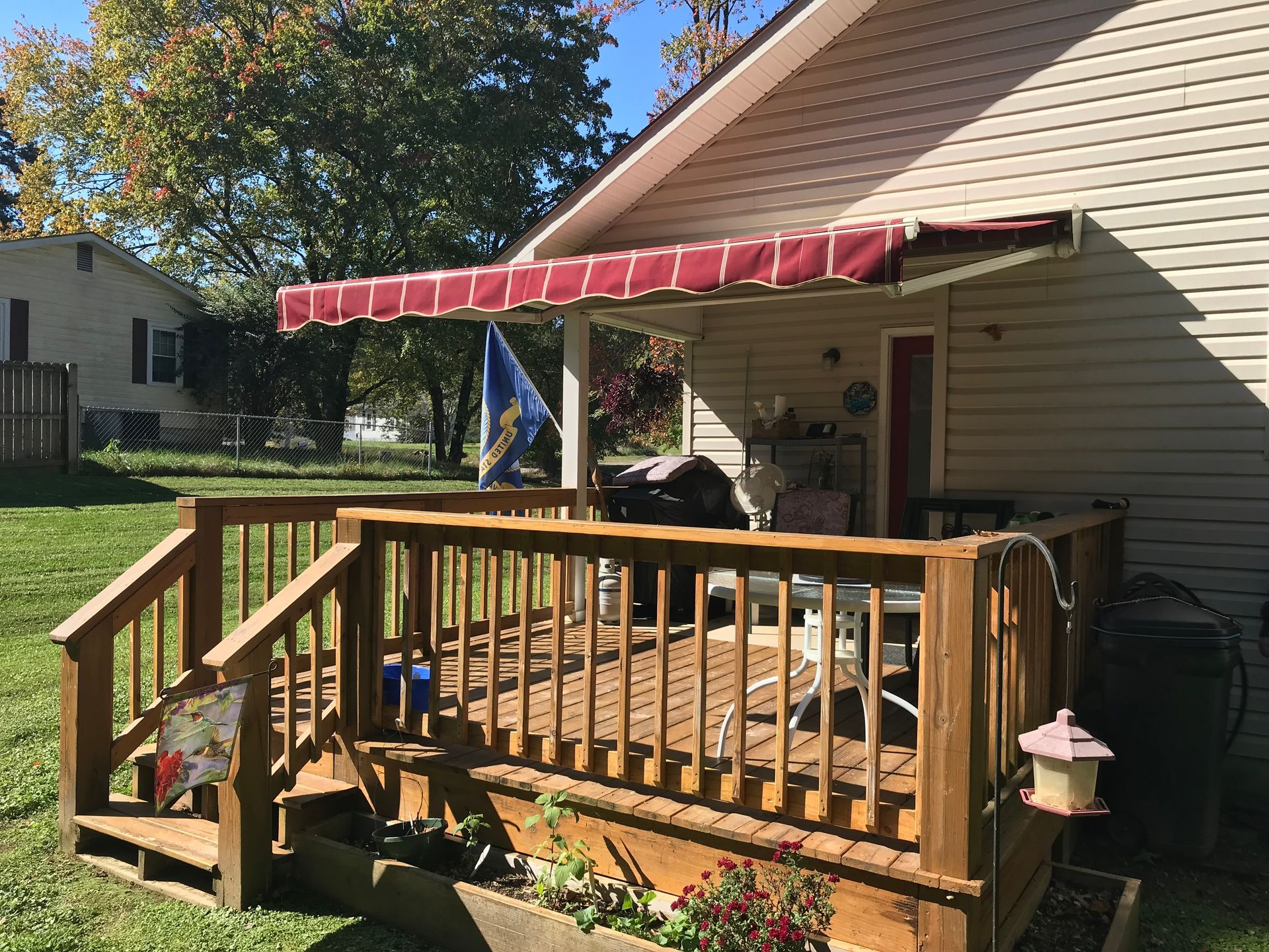 Wooden deck with red awning attached to a house.