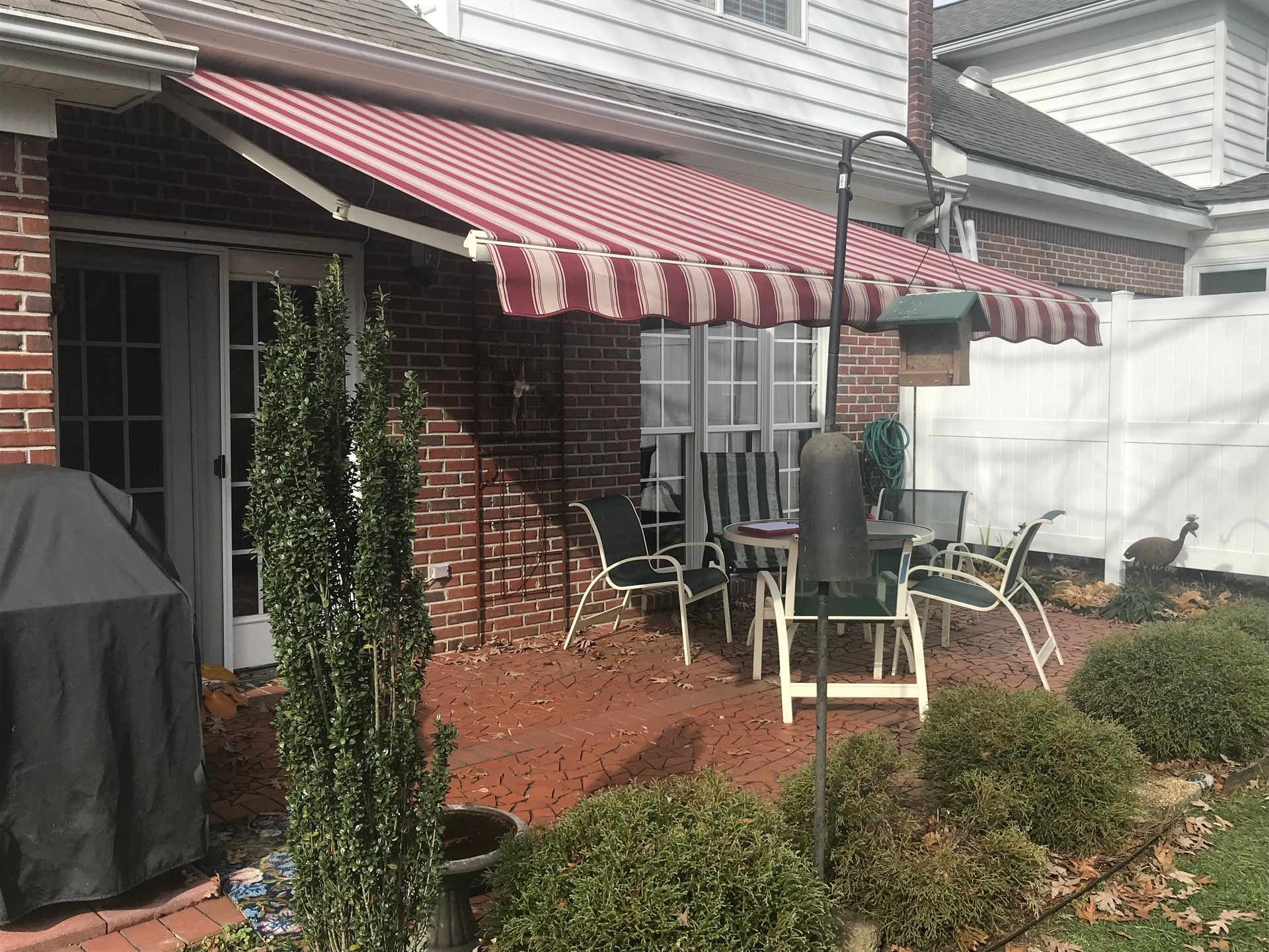 Red and white striped awning over a patio with outdoor furniture.
