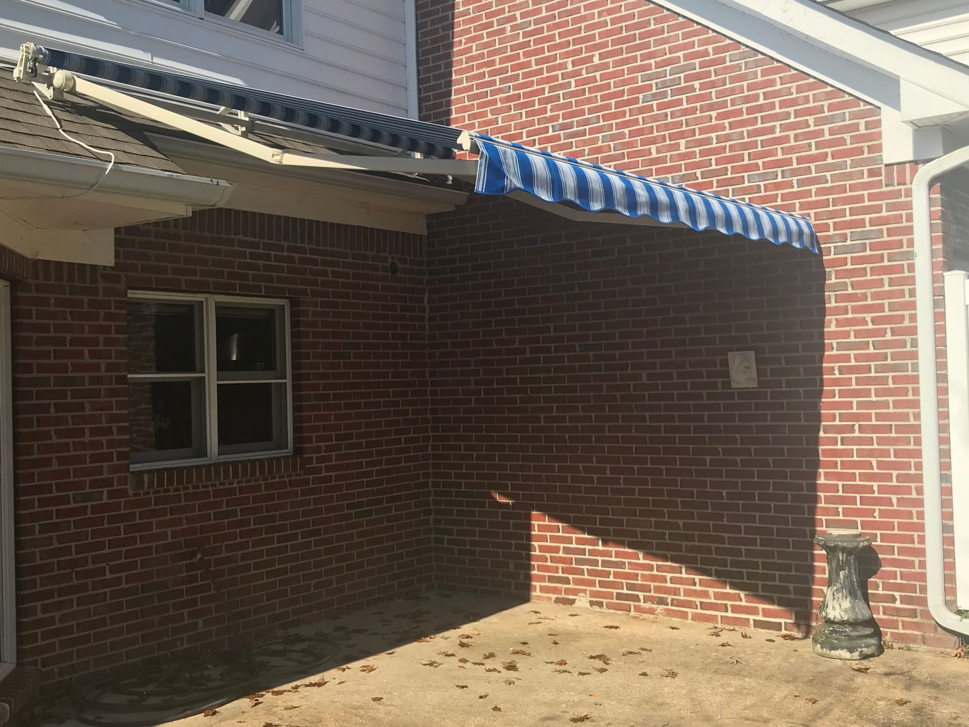 Brick building with blue and white striped awning. Window on left.