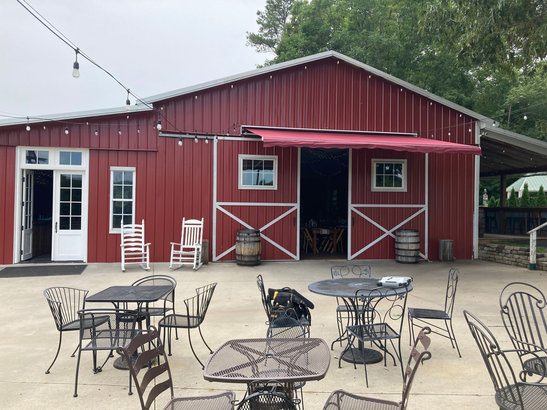 Red barn with outdoor seating. Metal tables and chairs in front.