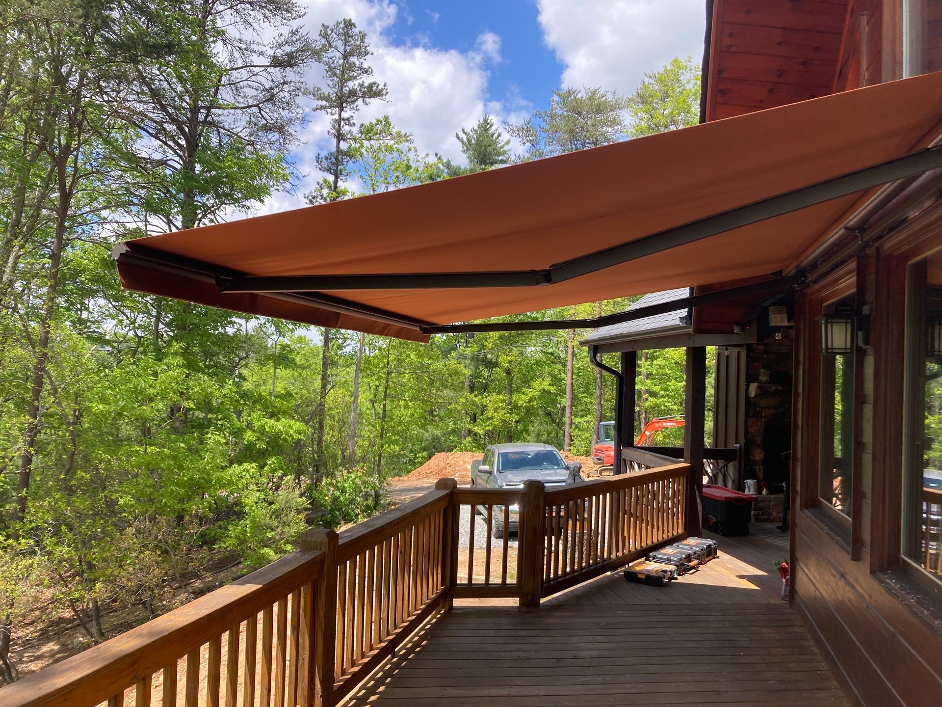 Orange awning over a wooden deck with a forest backdrop.