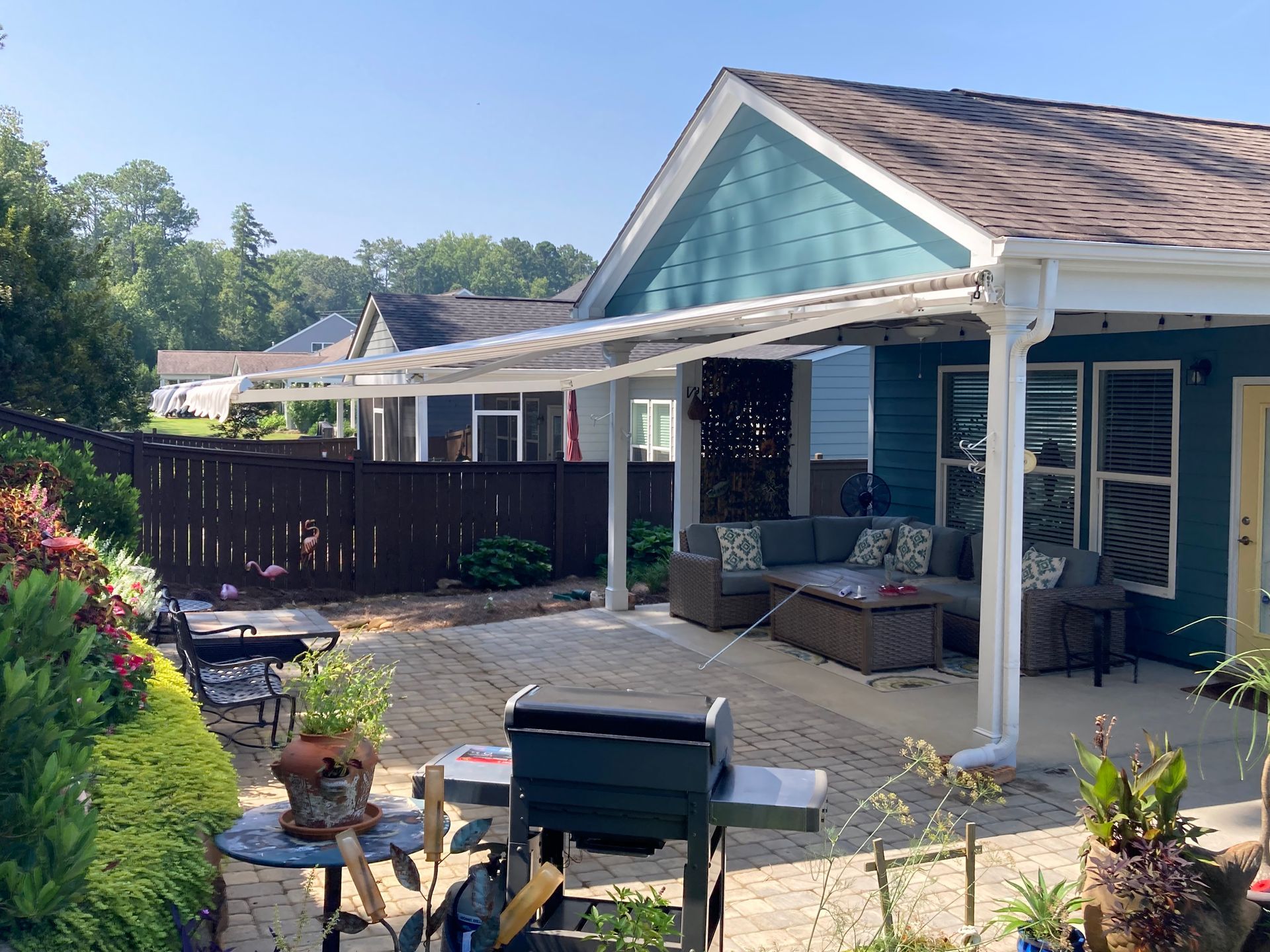Patio with awning, outdoor seating, grill, and house with blue siding.