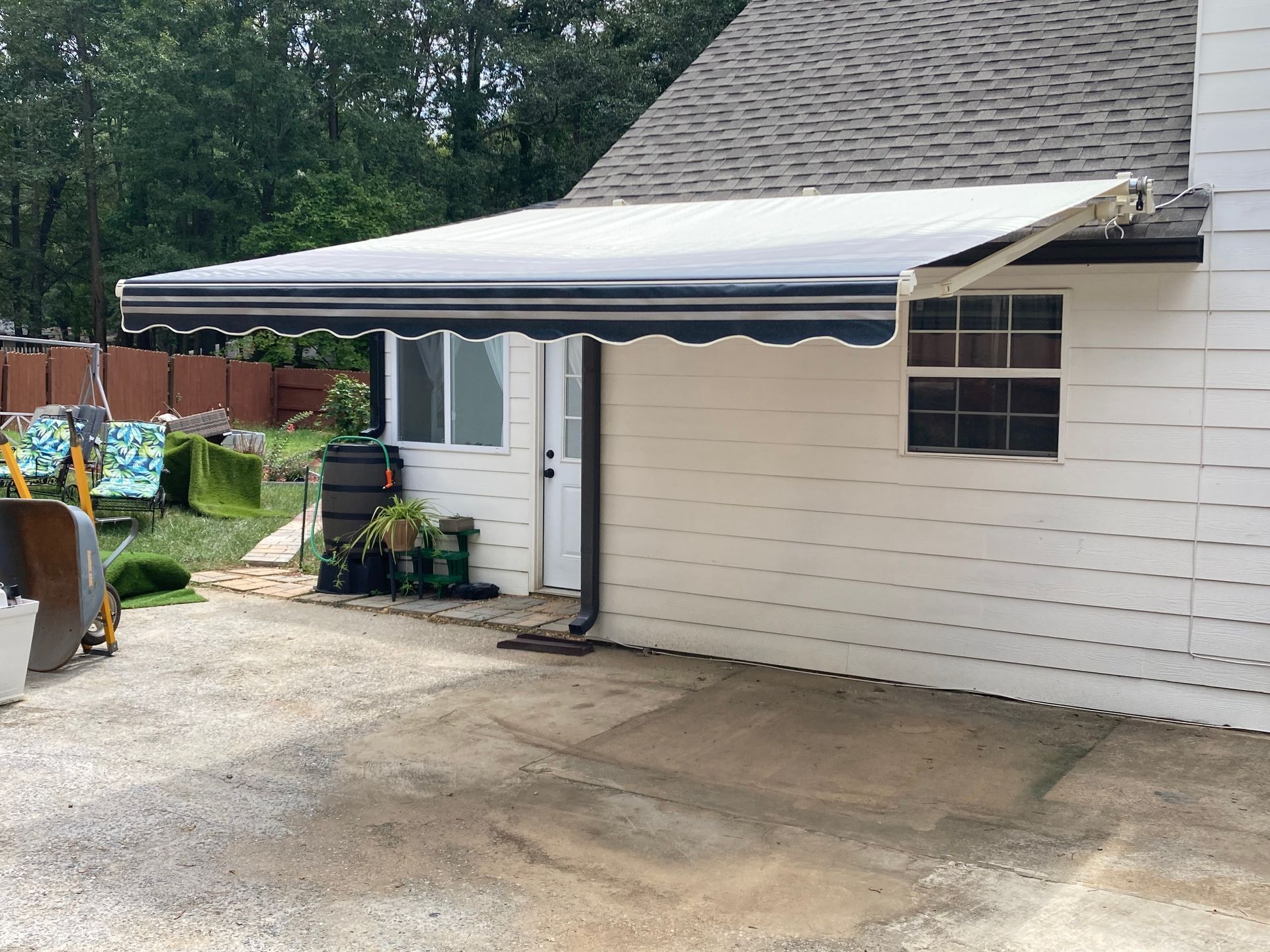 Retractable awning over a white building with black and white striped canopy.
