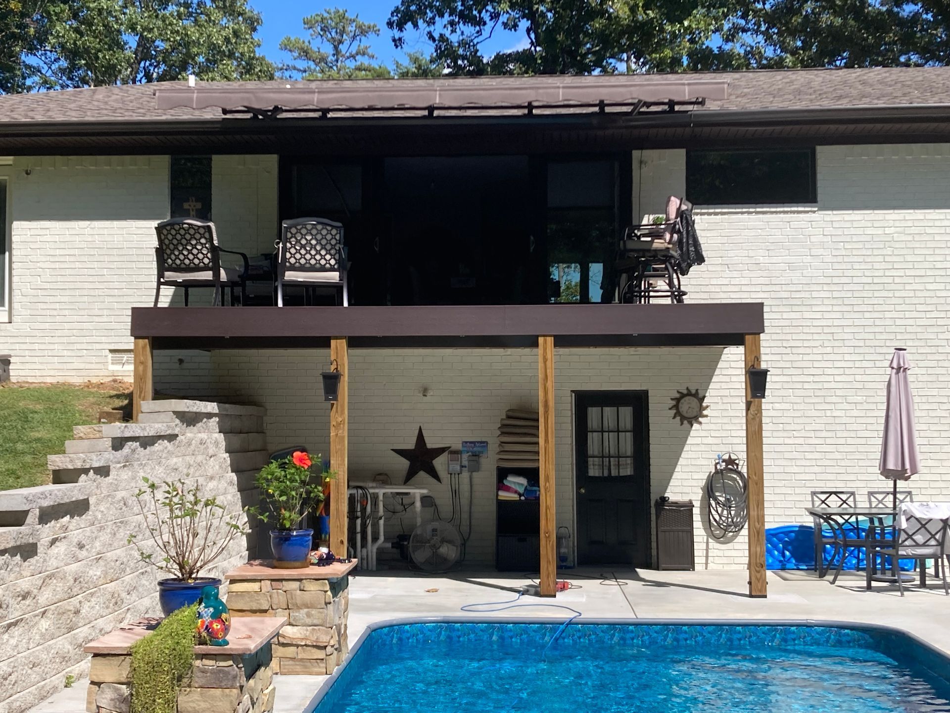 Backyard with a pool, deck, stairs, and patio furniture.