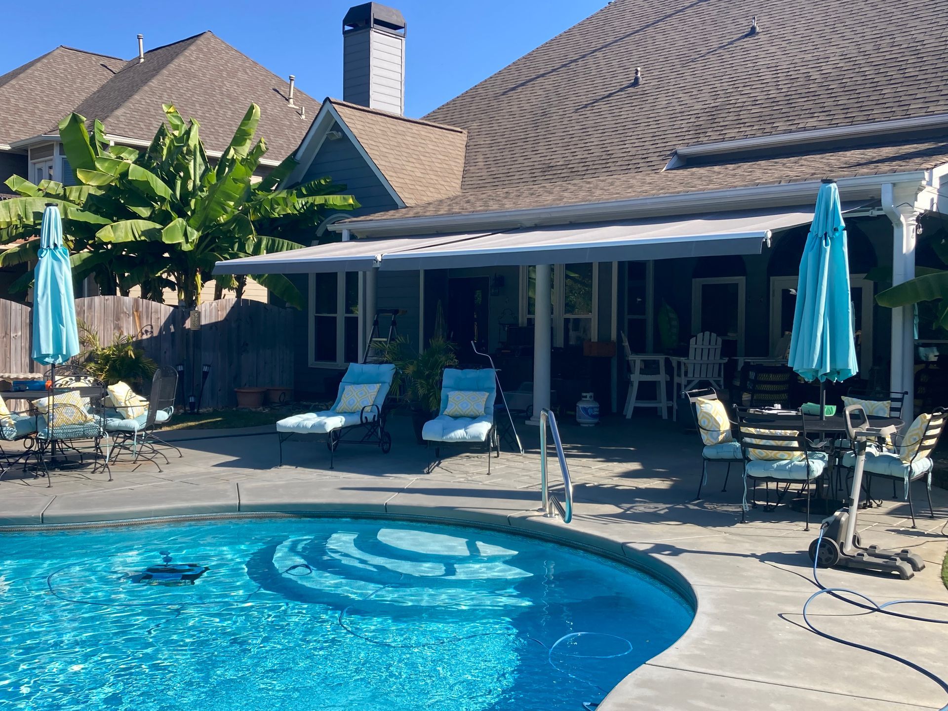 Poolside view of a house with a pool, lounge chairs, umbrellas, and outdoor seating.