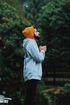 A man wearing a hoodie and an orange hat is praying in the rain.