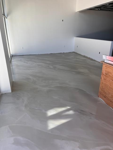 A large empty room with a concrete floor and white walls.