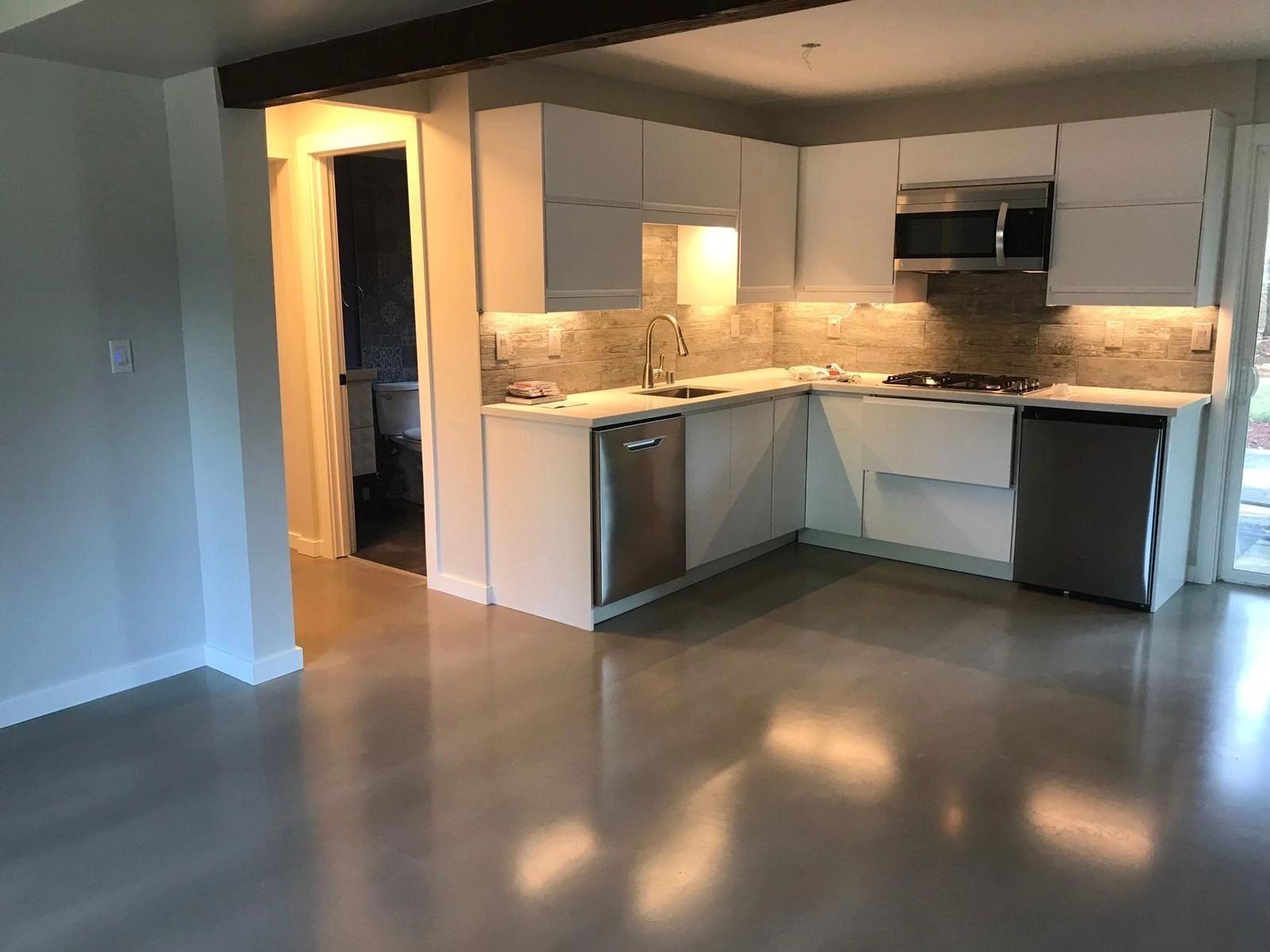 An empty kitchen with white cabinets and stainless steel appliances.