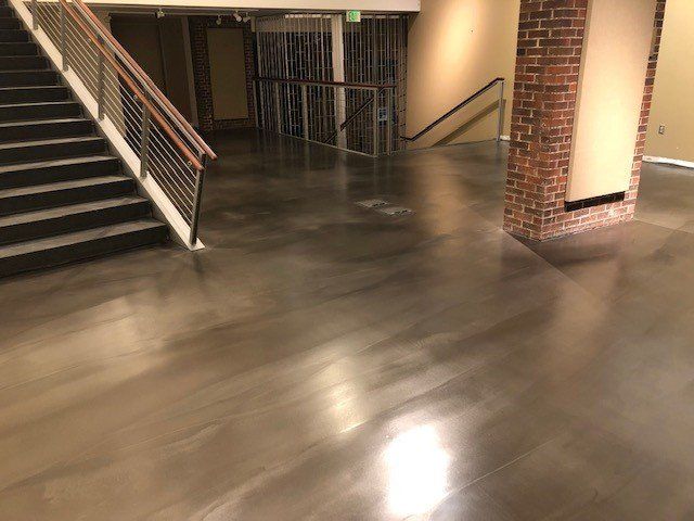 A hallway with stairs and a concrete floor