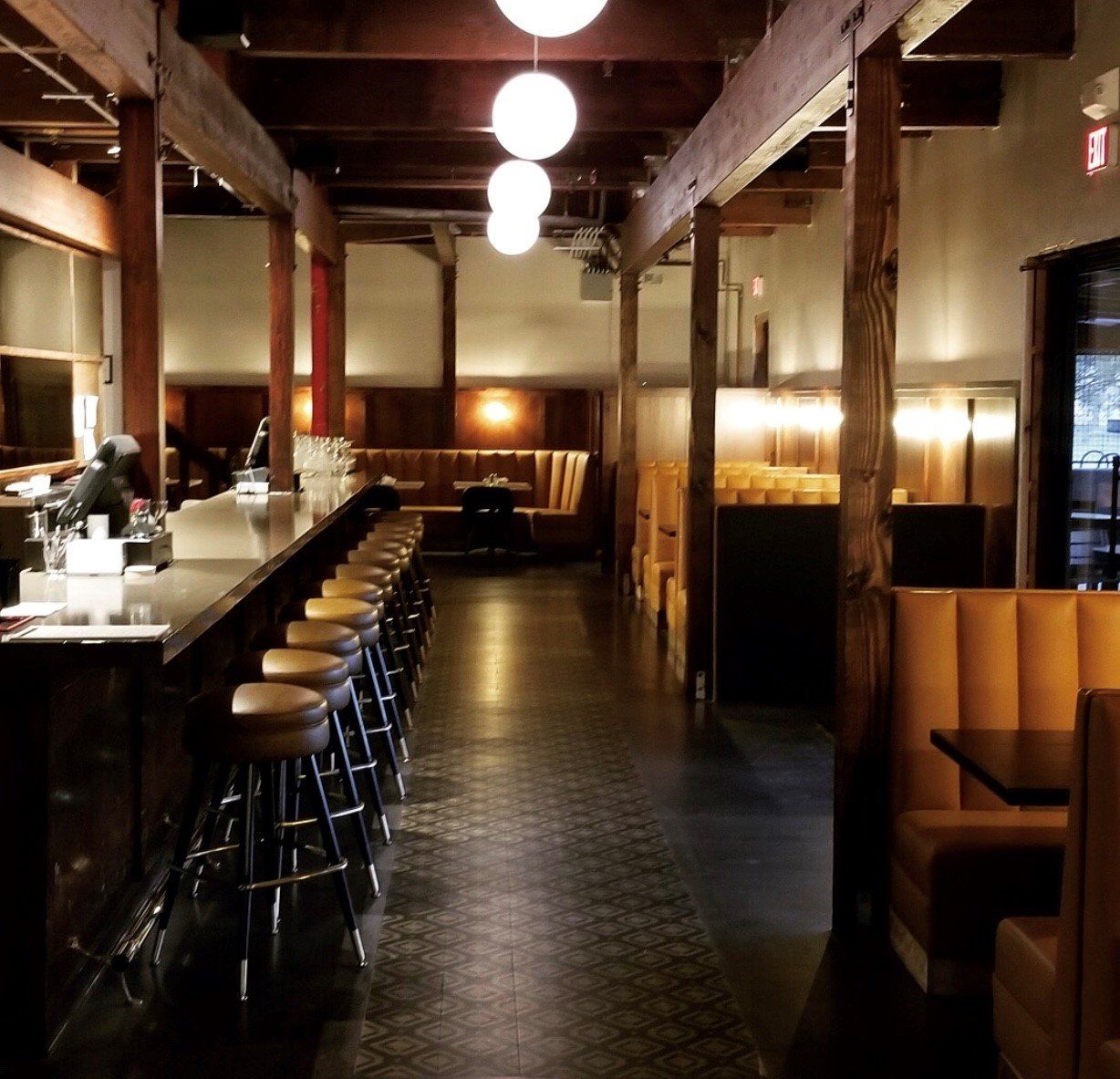 A long hallway in a restaurant with tables and stools