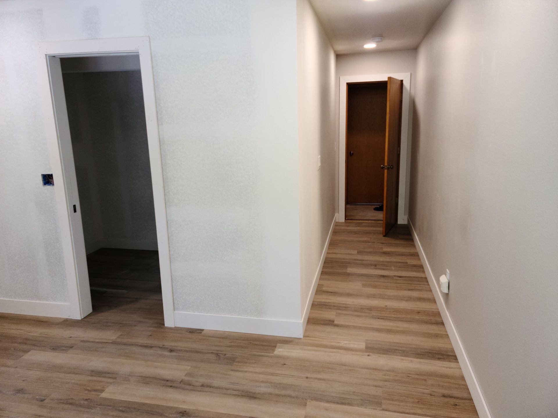 A long hallway with wooden floors and white walls