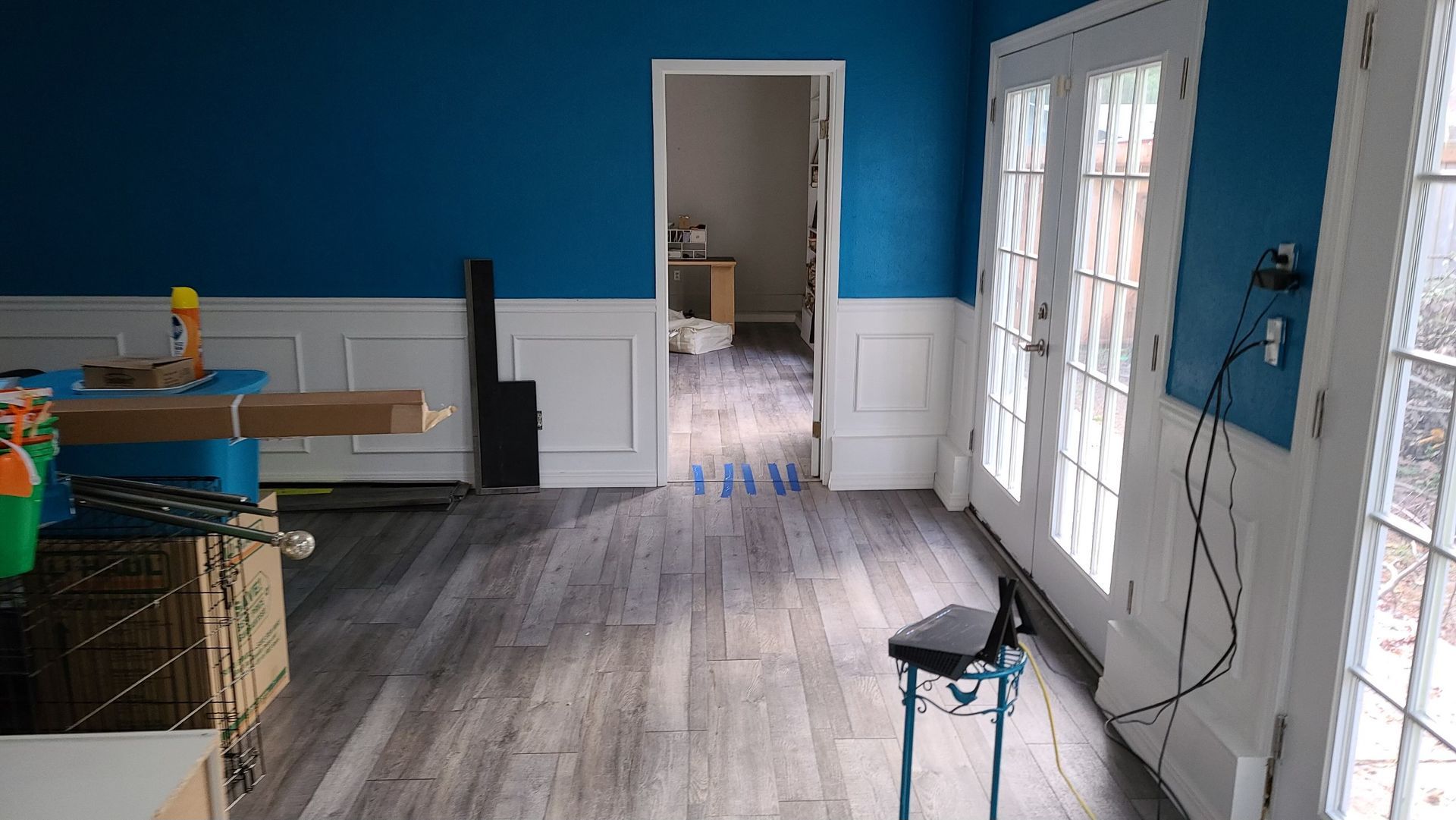 A room with blue walls and a wooden floor is being remodeled.