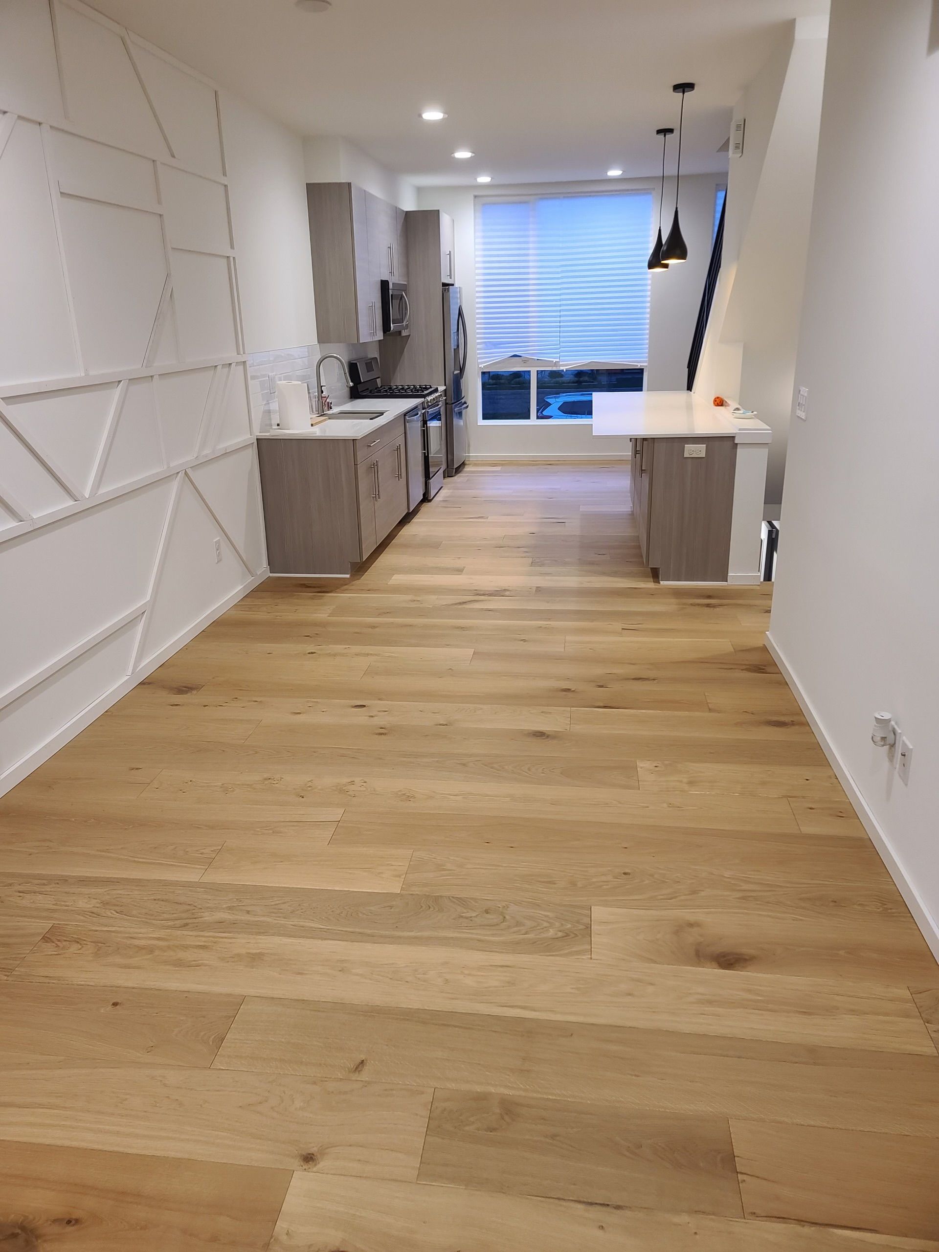A kitchen with hardwood floors and white walls.