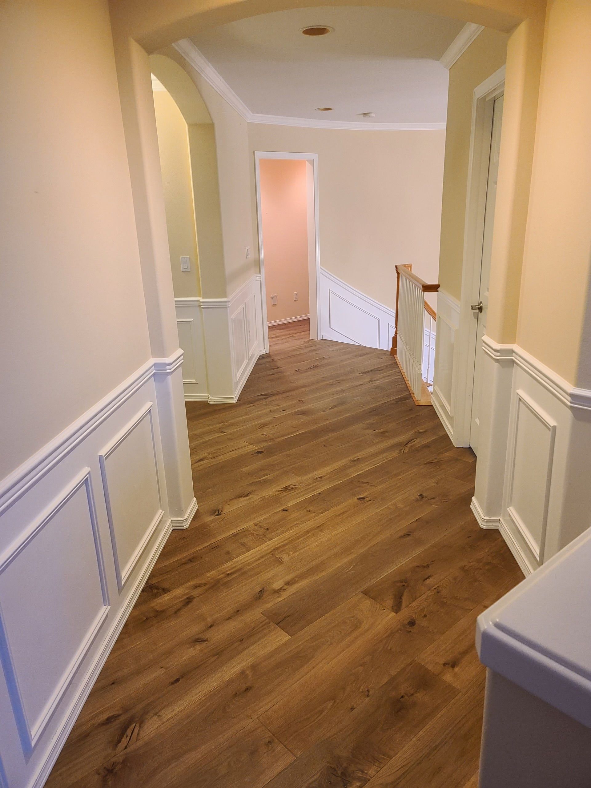 A hallway with a wooden floor and white trim