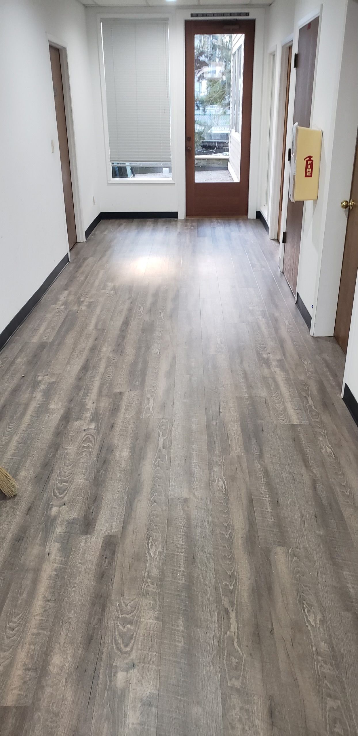 A long hallway with a wooden floor and a door.