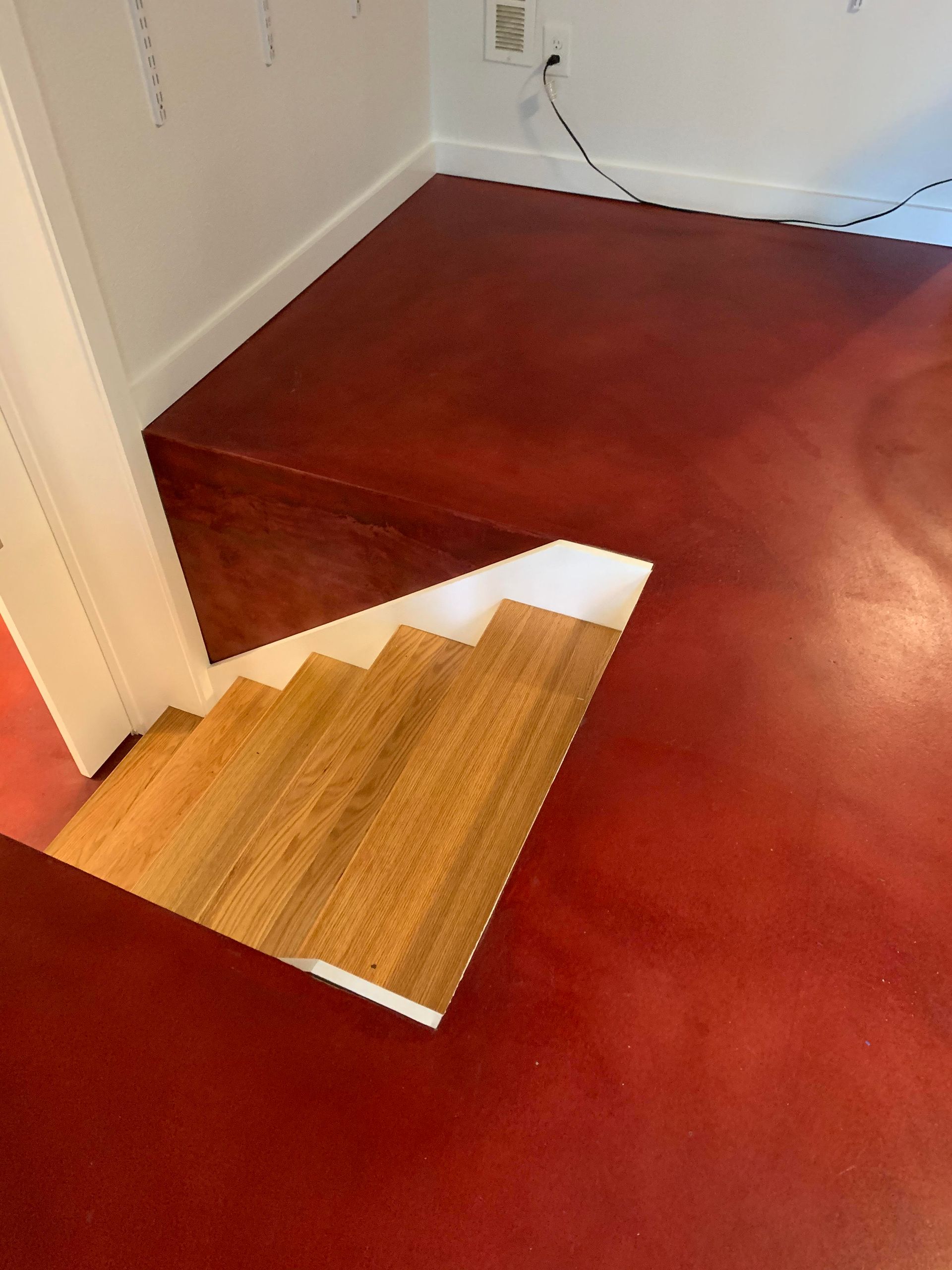 A red floor with wooden stairs in a room
