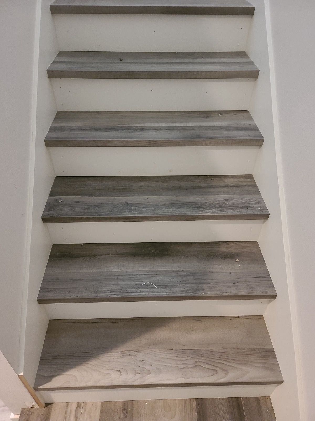 A set of stairs with wooden steps and a white wall.