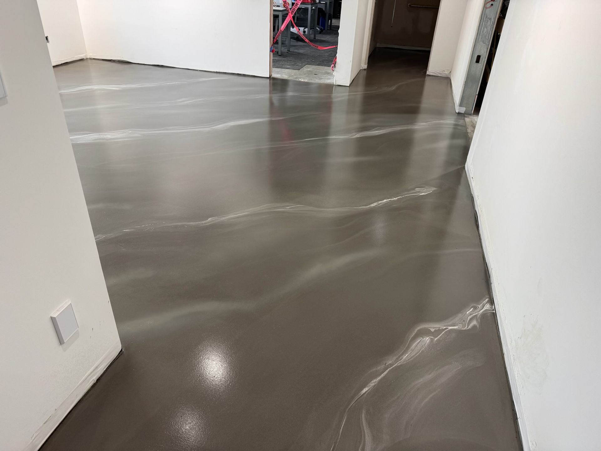 A hallway with a concrete floor and white walls.