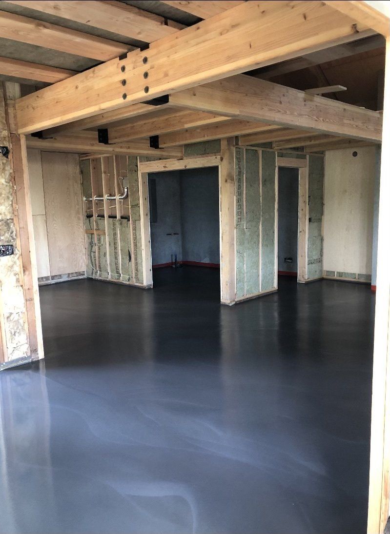 A large room with a concrete floor and wooden beams.